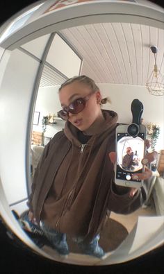 a woman taking a selfie with her cell phone in front of the camera mirror