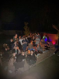 a group of people sitting around each other in front of a fire pit at night