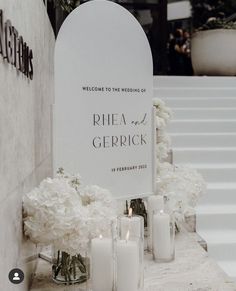 a wedding sign with flowers and candles in front of the entrance to a ceremony venue