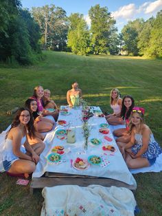 a group of women sitting at a picnic table with plates and drinks in front of them