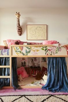 there is a bunk bed with curtains on the bottom and a giraffe head above it