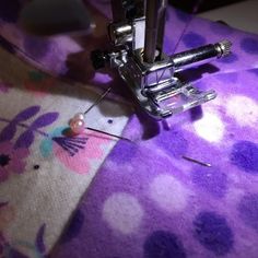 the sewing machine is working on the purple flowered material that has been sewn