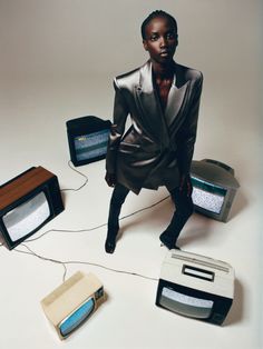 a woman standing in front of some old tvs and radio sets on a white surface