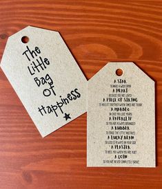 two tags that say the little bag of happiness are on top of a wooden table