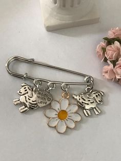 a close up of a flower and two charms on a white surface with pink flowers in the background