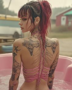 a woman with red hair and tattoos sitting in a pink bathtub full of water