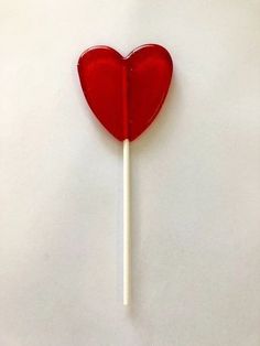 a red heart shaped lollipop on a stick