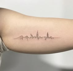 a woman's arm with a skyline tattoo on the left side of her arm