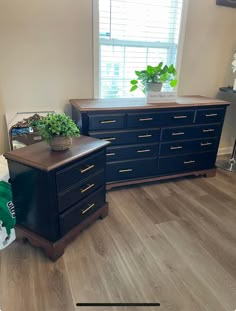 a bedroom with two dressers and a plant on the top shelf in front of it