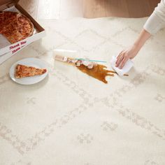 a person is cleaning the floor with a sponge and spatula next to two slices of pizza