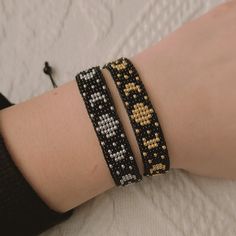 two bracelets are shown on someone's arm, one is black and the other is yellow