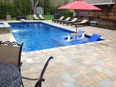 an image of a pool with chairs and umbrellas in the yard or patio area