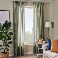 a living room filled with furniture and a window covered in green drapes next to a potted plant