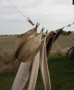 hats hanging on clothes line in grassy area next to bicycle and field with people riding bikes