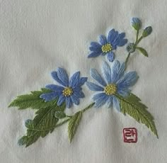 some blue flowers and green leaves on a white towel