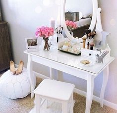 a white vanity with pink flowers on it and a large round mirror over the top