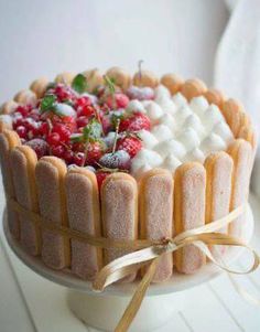 a cake decorated with marshmallows, strawberries and raspberries