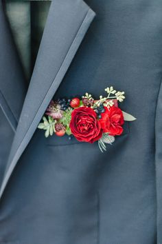 a man wearing a blue suit with red flowers on it's lapel pin