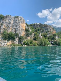 an island in the middle of water with trees growing on it's sides and cliffs