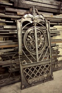 an ornate iron gate in front of stacks of wooden pallets and other metal items