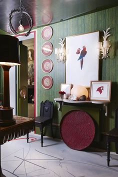 a living room with green walls and pictures on the wall, two chairs and a table