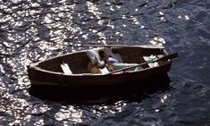 two people in a small boat floating on the water with sun reflecting off the water