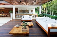 an outdoor living area with white couches and wooden tables