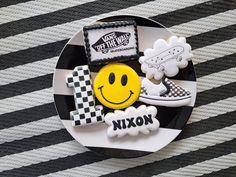 a black and white plate topped with cookies next to a yellow smiley face on a checkered table cloth