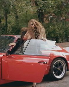 a woman leaning out the window of a red sports car