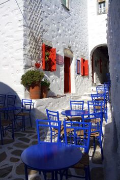 blue chairs and tables in front of a white building