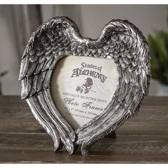 an angelic heart shaped photo frame sitting on top of a wooden table