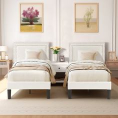 two beds in a room with white walls and wood flooring, one is made up to