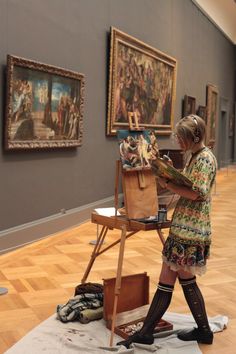 a woman is painting in an art gallery