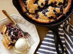 a blueberry cobbler with ice cream and a fork on a plate next to it