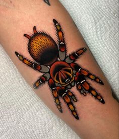 a close up of a tattoo on a person's leg with an orange and black spider