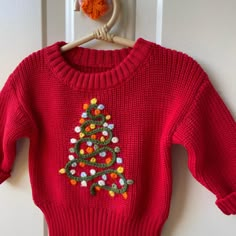 a red sweater with a christmas tree on it