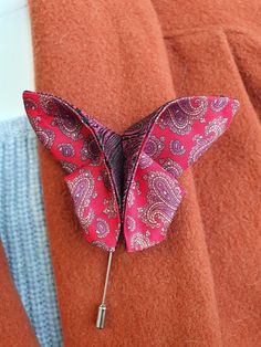 a close up of a person wearing a jacket with a butterfly brooch on it