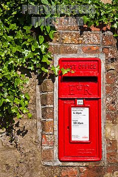 a red mailbox sitting on the side of a brick wall with ivy growing over it