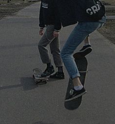 two young men riding skateboards down a sidewalk