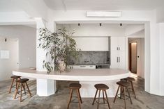 a kitchen with white counter tops and wooden stools in front of an island table