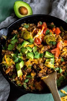 a skillet filled with ground beef, avocado, tomatoes and cilantro