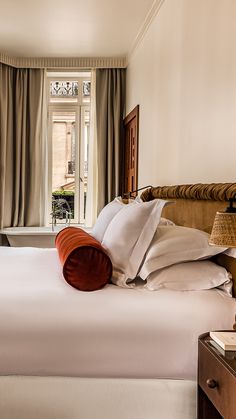 a bed with white sheets and pillows in a bedroom