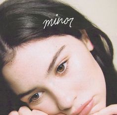 a woman with her hands on her face and the words minor above her head are in white lettering