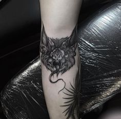 a black and white photo of a person with a tattoo on their leg that has a wolf's head on it