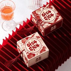 two red boxes sitting next to each other on top of a white table with wine glasses