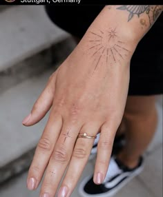 a person's hand with a tattoo on it, and the other hand has a ring