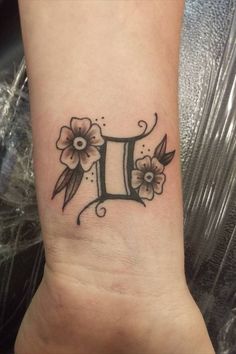 a black and white tattoo on the wrist with flowers around it's edges,