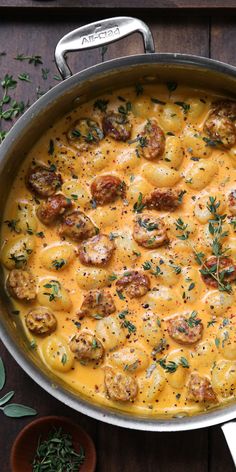 a pan filled with cheese and meat covered in sauce on top of a wooden table