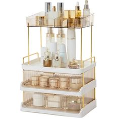 three tiered cosmetic organizer with gold accents and clear containers on the bottom shelf, along with other beauty products