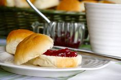 two rolls with jam on them sitting on a plate next to a bowl of jelly